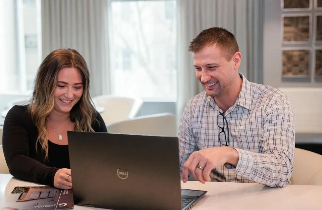 A man and woman looking at a laptop.